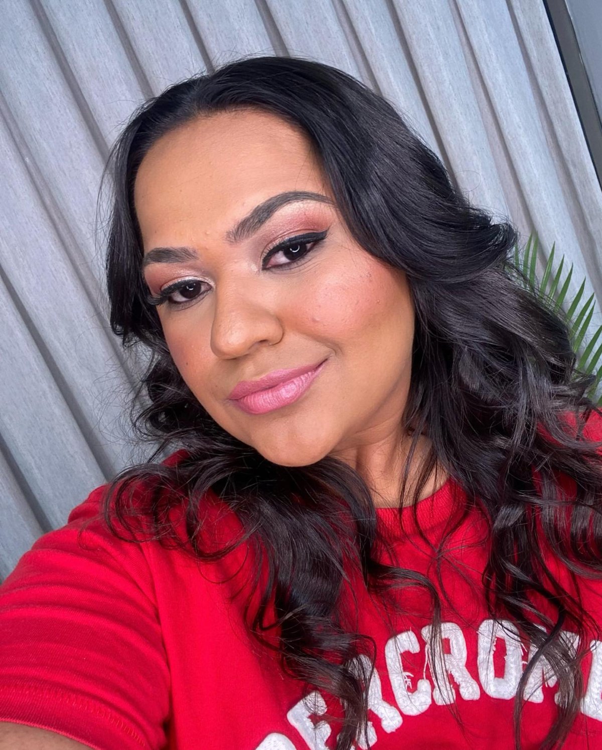 Ondas volumosas em cabelo escuro com maquiagem em tons rosados
