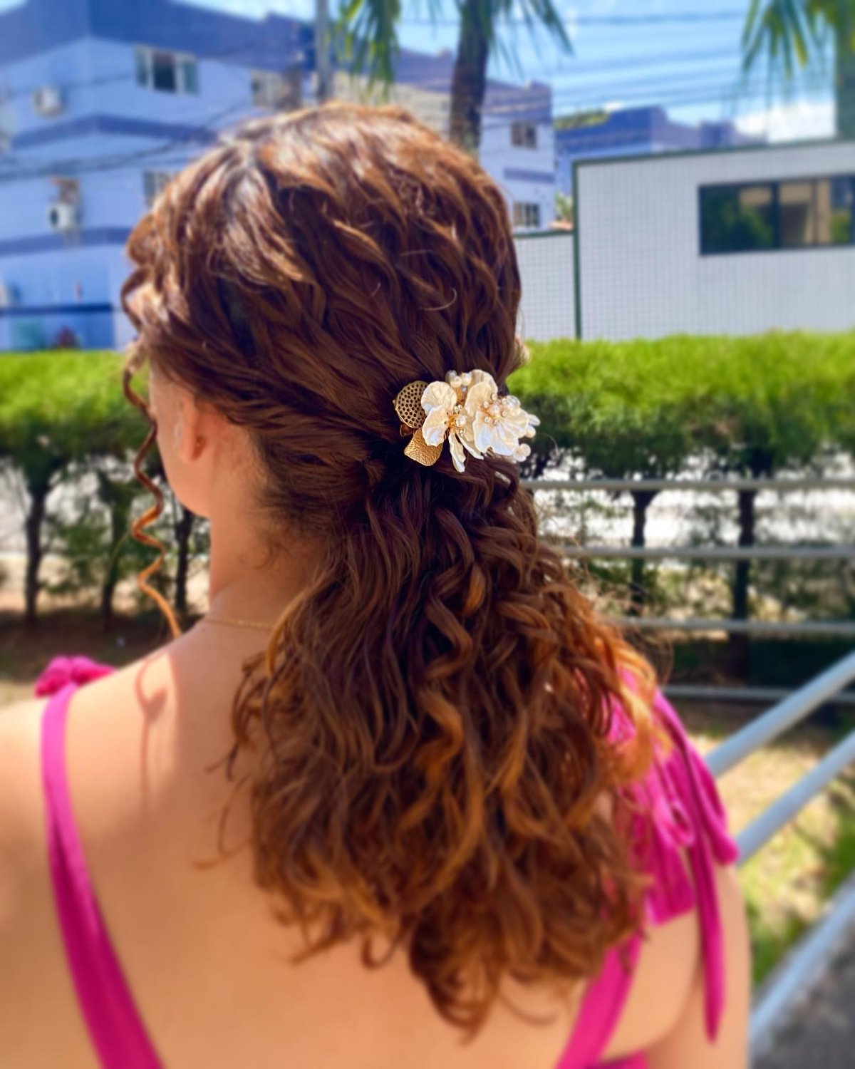 Penteado semipreso em cabelo cacheado ruivo com presilha de flores
